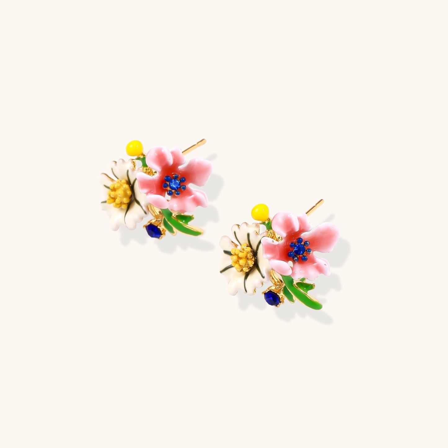 Detailed view of gold-plated brass stud earrings featuring multicolor enamel flowers with white, pink, and blue petals