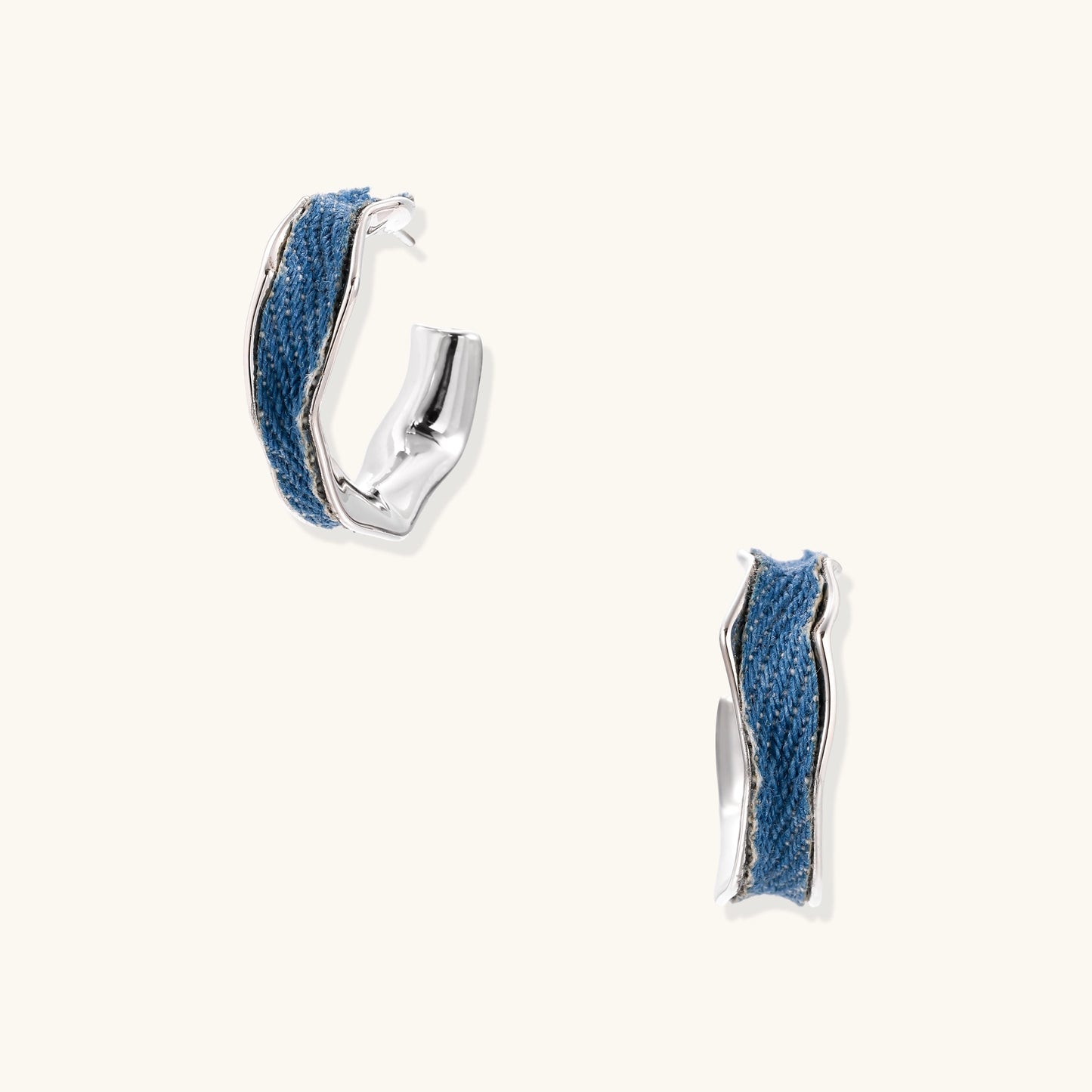 Small gold-plated hoop earrings with blue denim fabric insets on white background, showing casual-luxe styling.