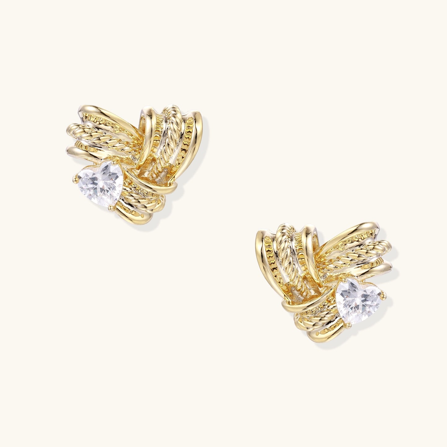 Close-up of gold-plated twisted rope design stud earrings with clear zirconia crystals on white background.