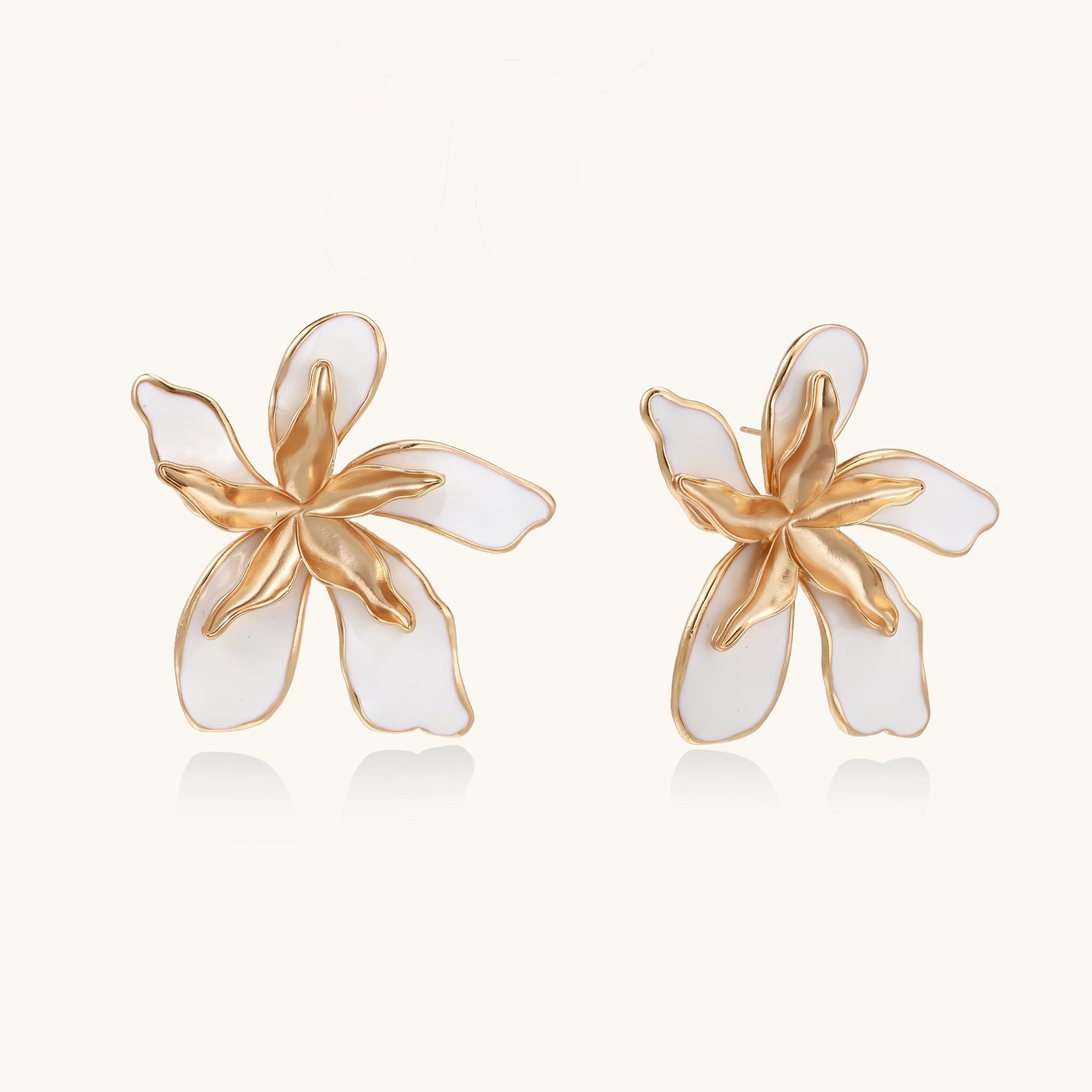 Large floral stud earrings with gold-plated brass petals and white enamel centers on neutral background