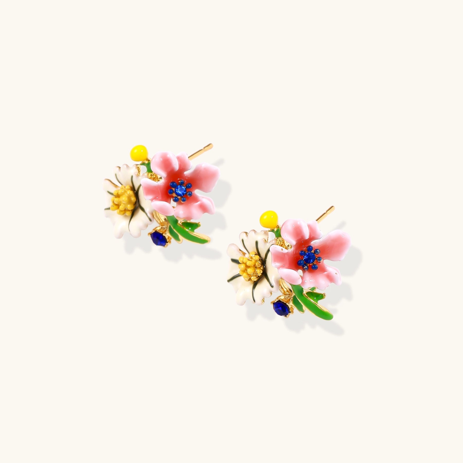 Detailed view of gold-plated brass stud earrings featuring multicolor enamel flowers with white, pink, and blue petals