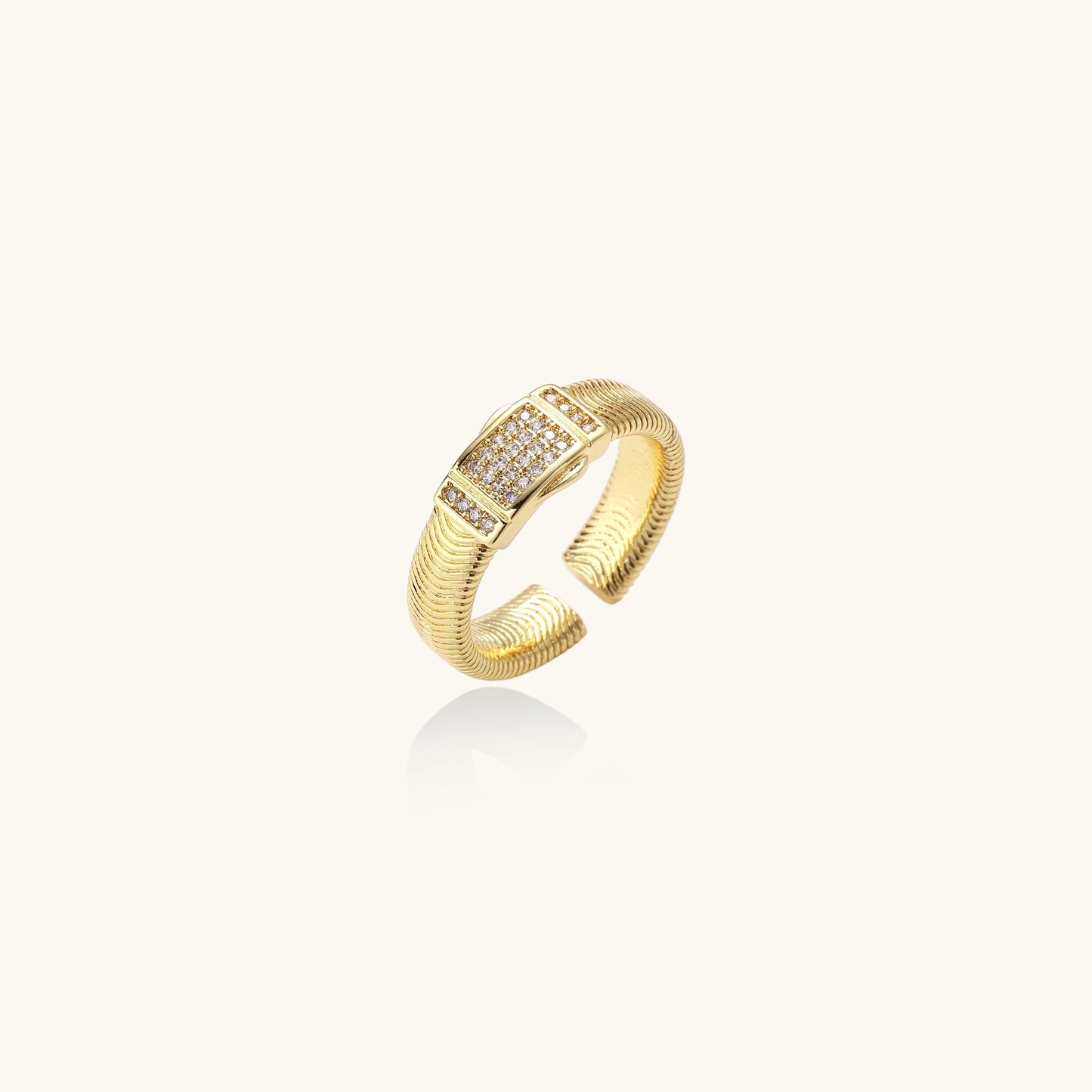 Gold-plated brass cuff ring with textured band and rectangular cubic zirconia centerpiece on cream background