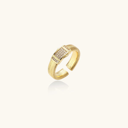 Gold-plated brass cuff ring with textured band and rectangular cubic zirconia centerpiece on cream background