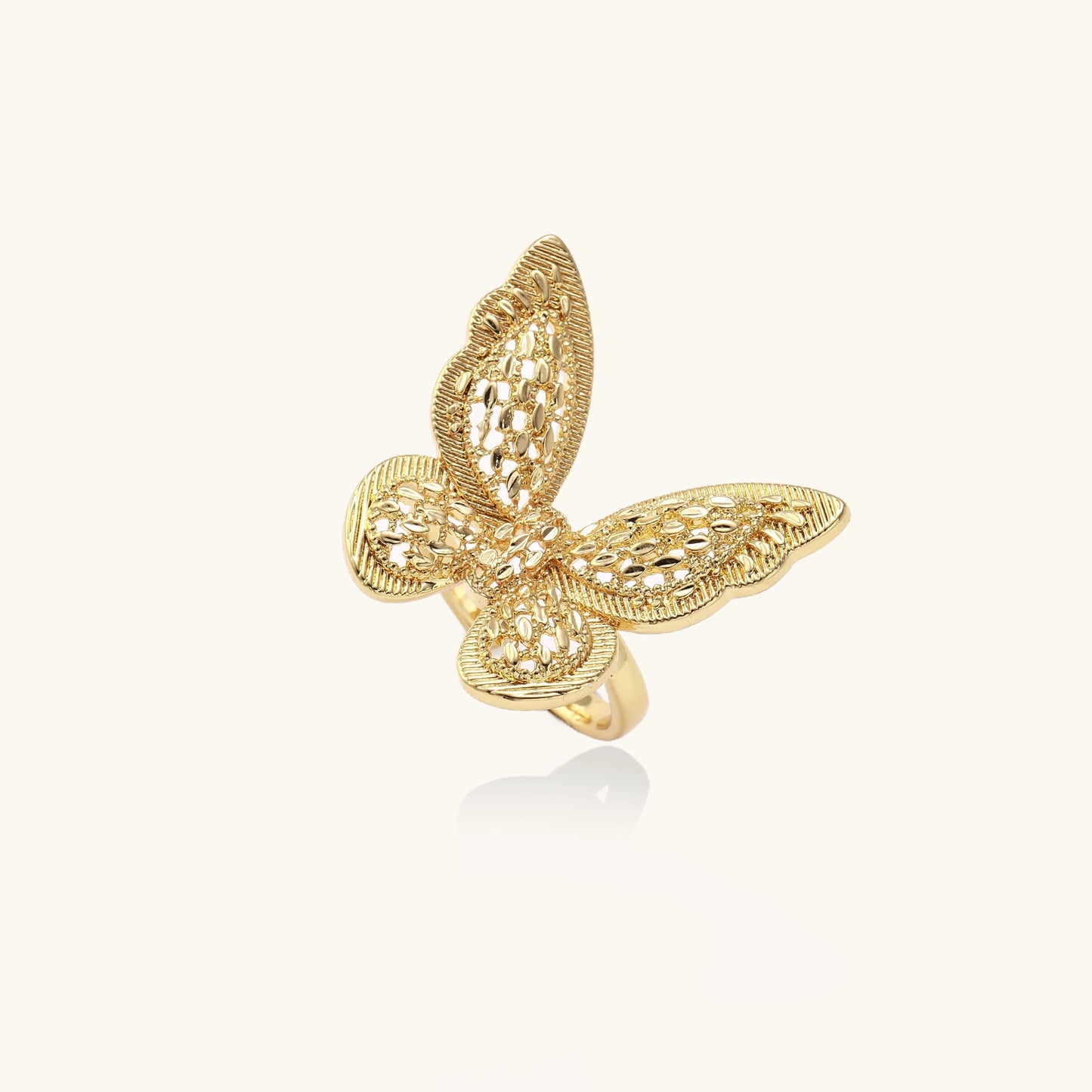 Adjustable gold-plated brass butterfly ring with intricate filigree cutout patterns and cubic zirconia accents on white background.