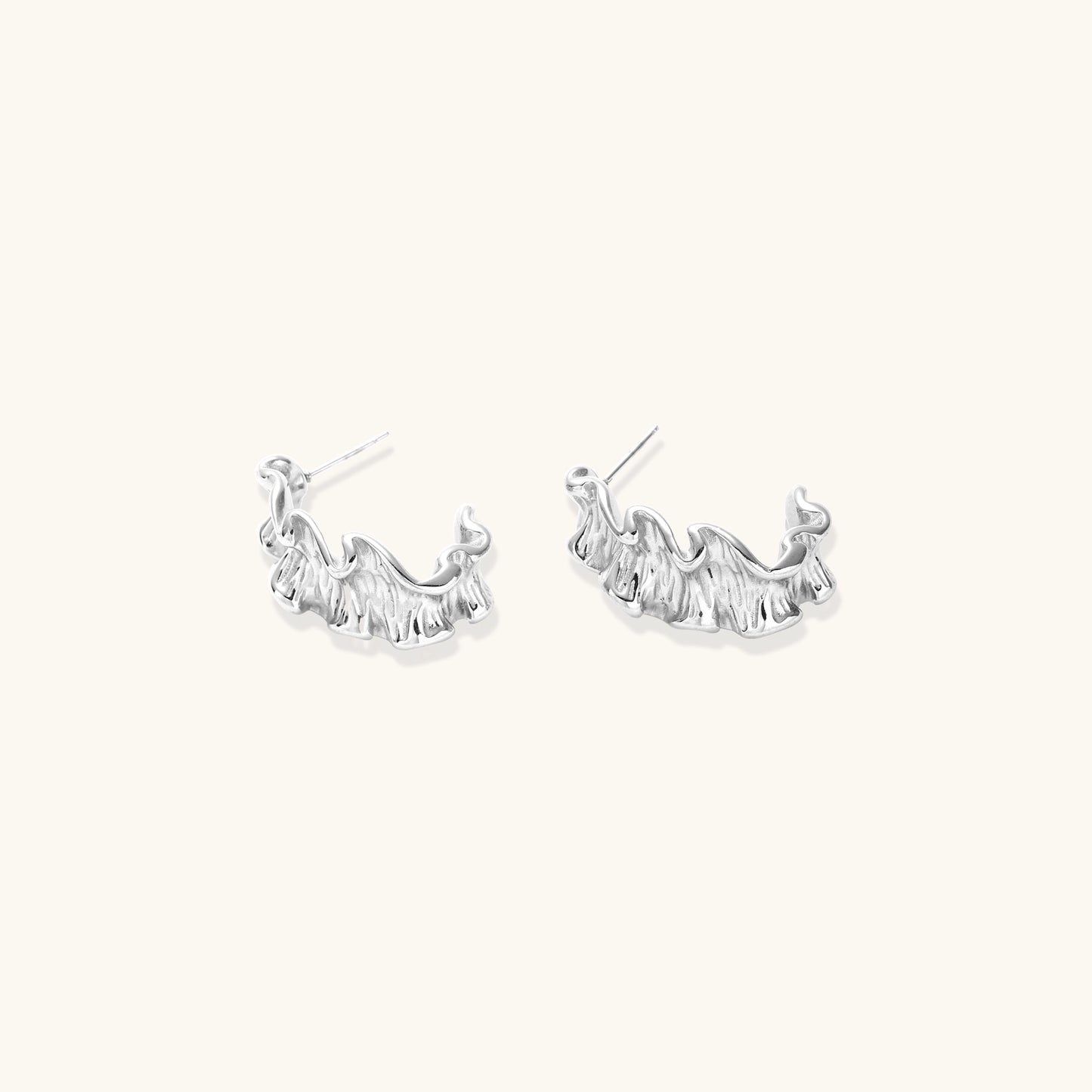 Textured gold-plated hoop earrings with flowing ripple design displayed on clean white background.