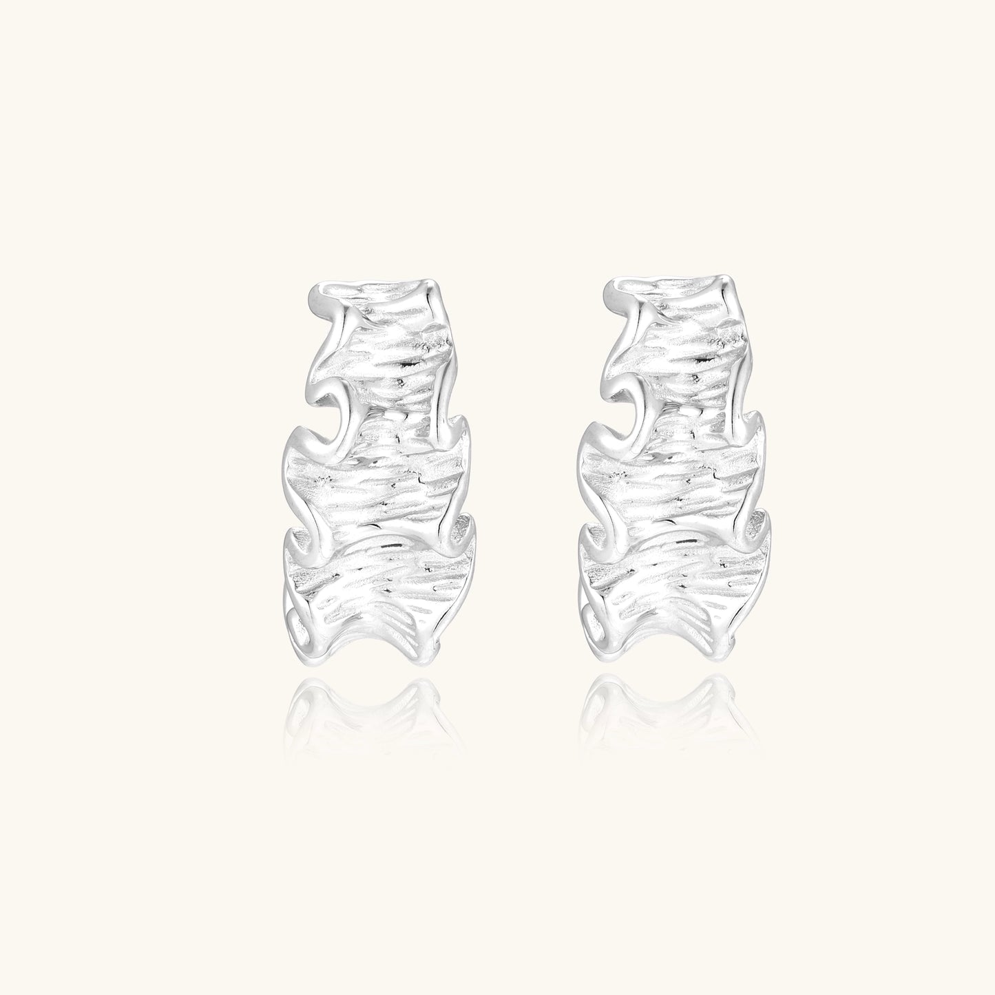Textured gold-plated hoop earrings with flowing ripple design displayed on clean white background.