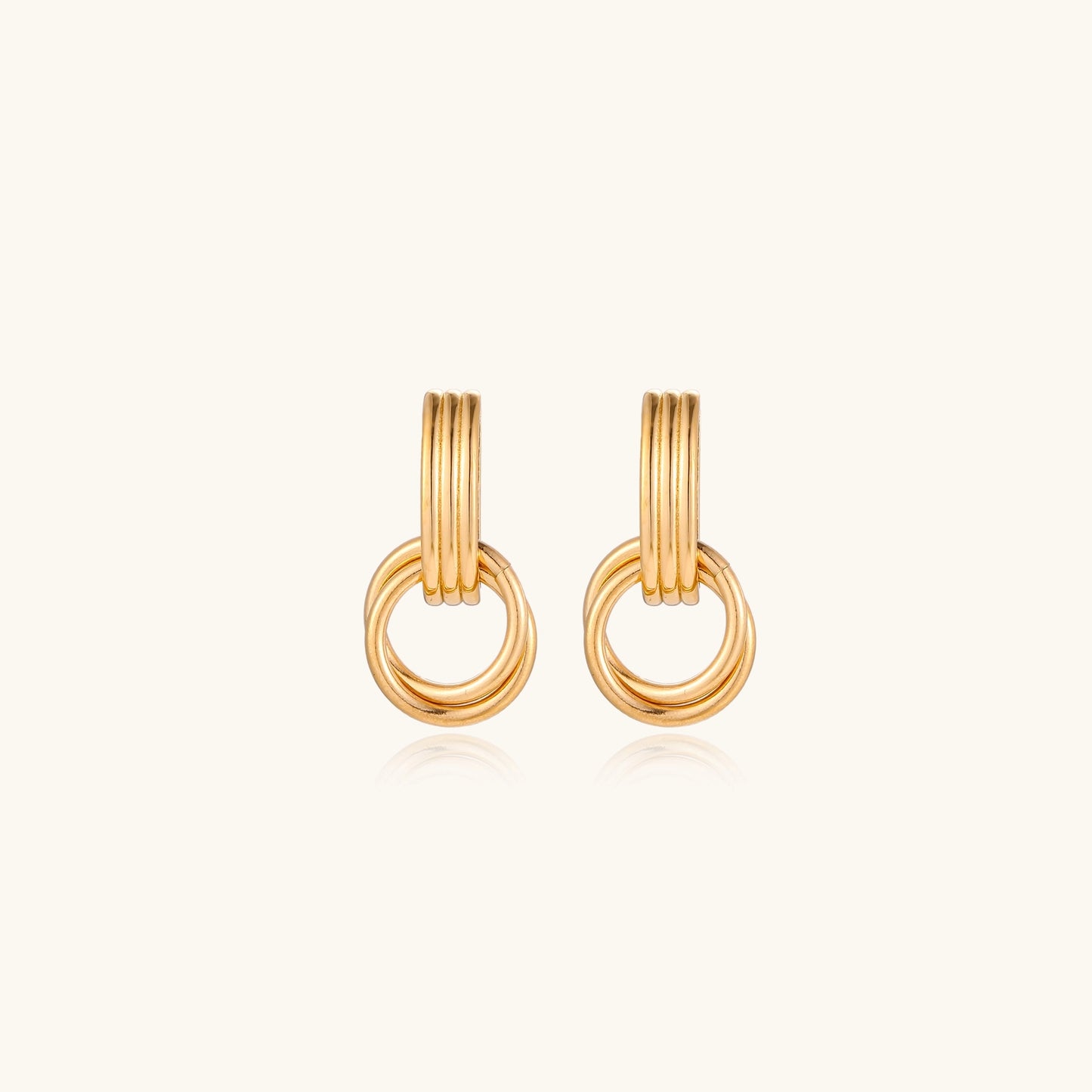 Geometric gold earrings with ribbed linear top section and circular drop elements on white background.
