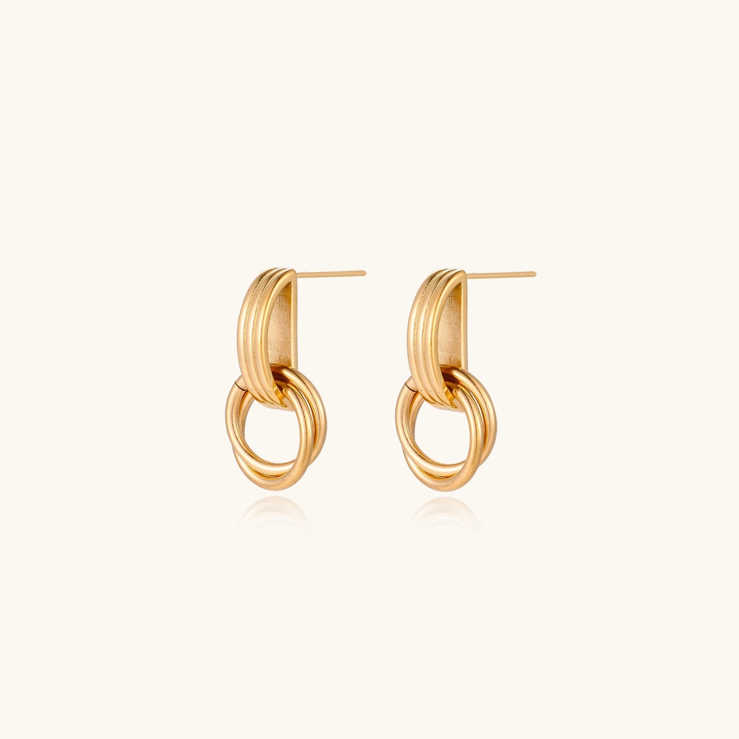 Geometric gold earrings with ribbed linear top section and circular drop elements on white background.