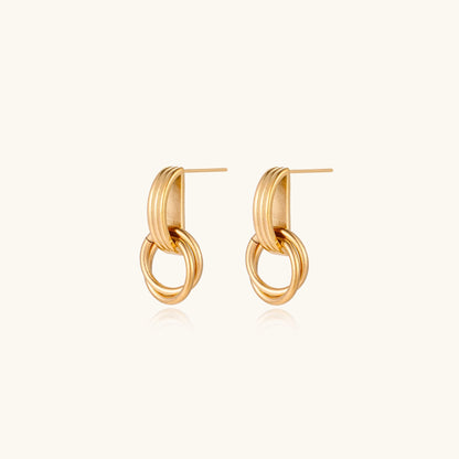 Geometric gold earrings with ribbed linear top section and circular drop elements on white background.