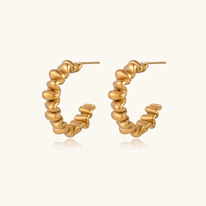 Gold-plated stainless steel earrings with twisted rope texture in various hoop sizes on neutral background.
