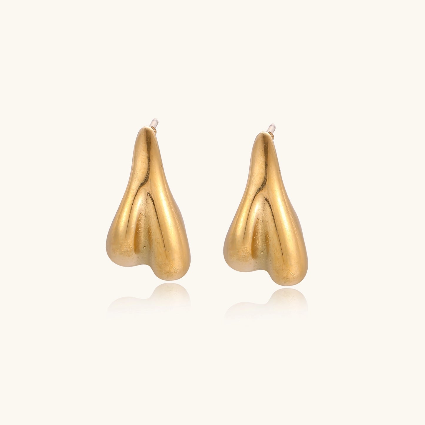 Pair of gold-plated sculptural stud earrings with organic teardrop shapes on neutral background.