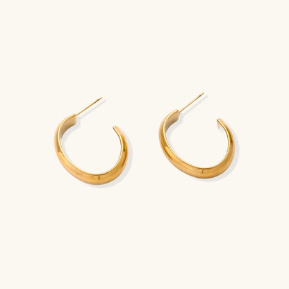 Four pairs of gold-plated stainless steel earrings including hoops and studs displayed on cream background