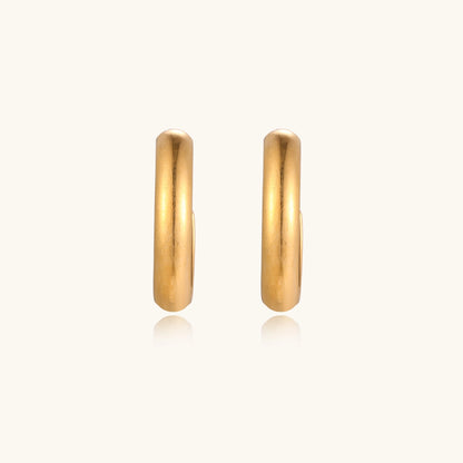 Four pairs of gold-plated stainless steel earrings including hoops and studs displayed on cream background